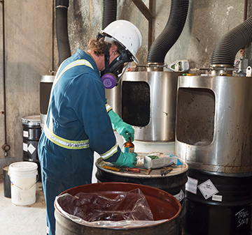 An operator removes waste consolidated in drums prior to processing